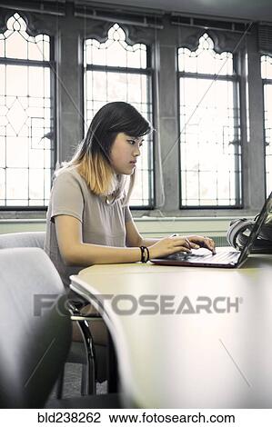 Chinese woman sitting in library using laptop View Large Photo Image Stock Image - Chinese woman sitting in library using laptop. Fotosearch