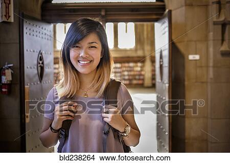 Chinese woman standing in library carrying backpack View Large Photo Image Picture - Chinese woman standing in library carrying backpack. Fotosearch