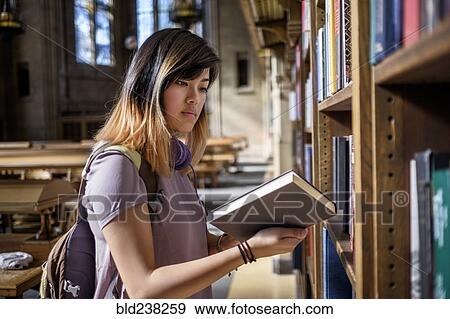 Stock Photo - Chinese woman standing in library reading book. Fotosearch