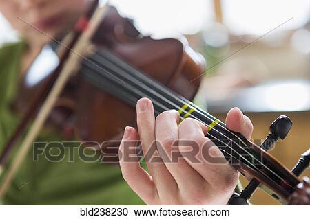 Stock Image - Close up of Caucasian girl playing violin. Fotosearch