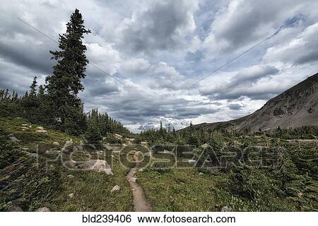 Stock Photograph - Clouds over trail in rocky landscape. Fotosearch
