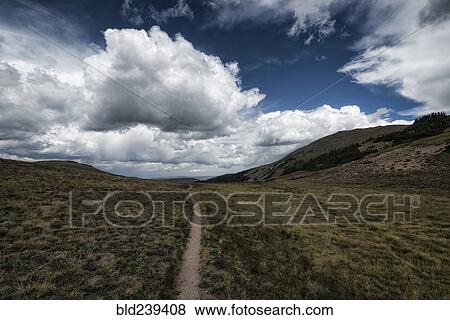 Clouds over trail in rolling landscape View Large Photo Image Stock Photo - Clouds over trail in rolling landscape. Fotosearch