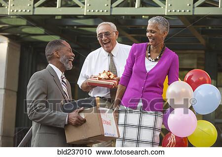 Co-workers celebrating with retiring man carrying belongings View Large Photo Image Stock Image - Co-workers celebrating with retiring man carrying belongings. Fotosearch