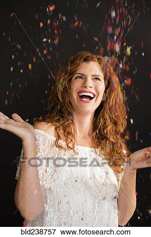 Stock Photo - Confetti falling on celebrating Caucasian woman. Fotosearch
