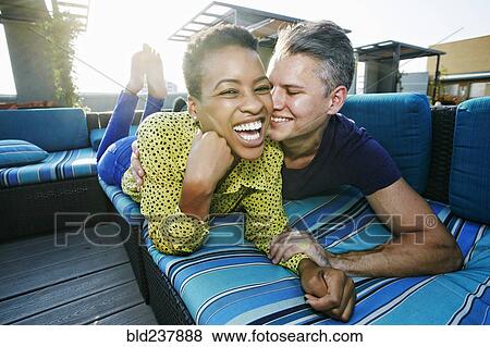 Couple cuddling on rooftop sofa View Large Photo Image Stock Photo - Couple cuddling on rooftop sofa. Fotosearch