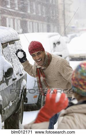 Stock Image - Couple having snowball fight in city. Fotosearch