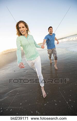 Couple holding hands running on beach View Large Photo Image Stock Image - Couple holding hands running on beach. Fotosearch