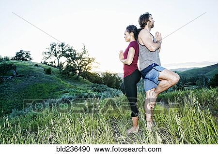 Stock Image - Couple practicing yoga on hill. Fotosearch
