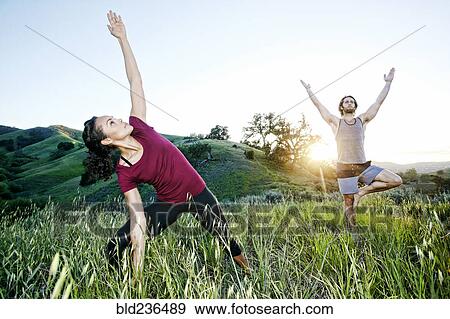 Stock Photo - Couple practicing yoga on hill. Fotosearch