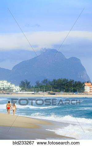 Stock Photo - Couple walking on beach near waves. Fotosearch