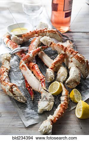 Picture - Crab legs and lemon slices on newspaper. Fotosearch