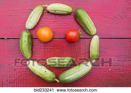 Stock Image - Cucumbers and tomatoes arranged in smiley face. Fotosearch