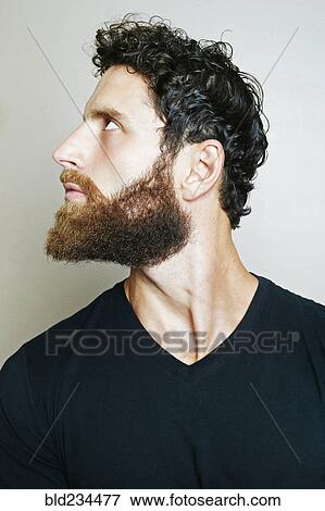 Stock Photo - Curious Caucasian man with beard looking up. Fotosearch