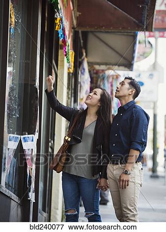Stock Photo - Curious Chinese couple window shopping in city. Fotosearch