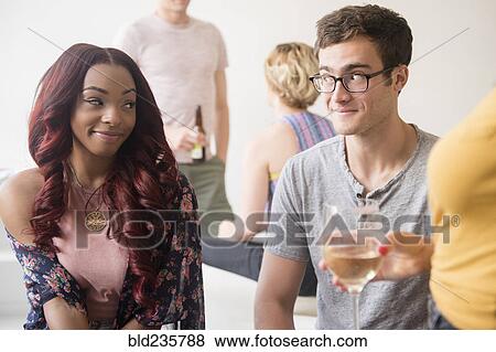 Stock Photo - Curious couple flirting at party. Fotosearch