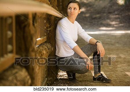 Curious woman crouching on forest path View Large Photo Image Stock Photo - Curious woman crouching on forest path. Fotosearch
