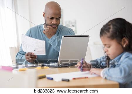 Stock Image - Daughter coloring with crayons while father uses laptop. Fotosearch