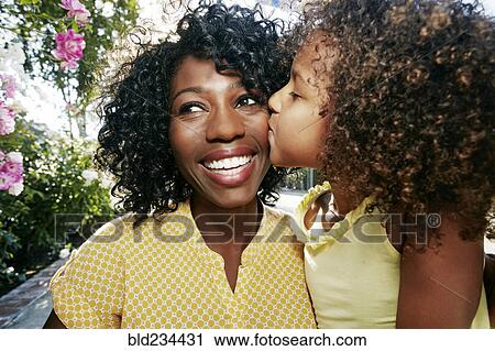 Daughter kissing cheek of mother outdoors View Large Photo Image Stock Image - Daughter kissing cheek of mother outdoors. Fotosearch