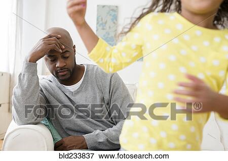 Daughter playing while father has headache View Large Photo Image Stock Photo - Daughter playing while father has headache. Fotosearch