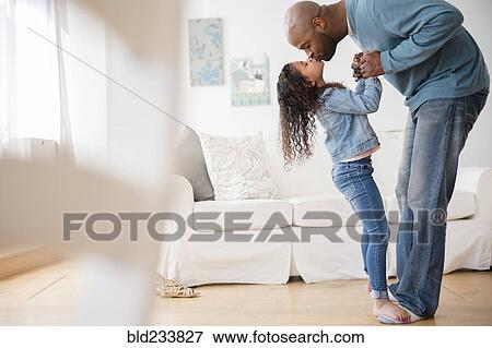 Stock Photo - Daughter standing on feet of father and dancing. Fotosearch
