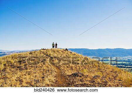 Distant Caucasian couple standing on hill holding hands View Large Photo Image Stock Photograph - Distant Caucasian couple standing on hill holding hands. Fotosearch