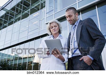 Picture - Doctor and businessman using digital tablet outdoors. Fotosearch