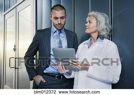 Stock Image - Doctor and businessman using digital tablet outdoors. Fotosearch