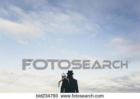 Stock Image - Drone on shoulder of man watching birds fly. Fotosearch