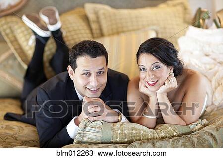 Stock Image - Egyptian bride and groom laying on bed. Fotosearch