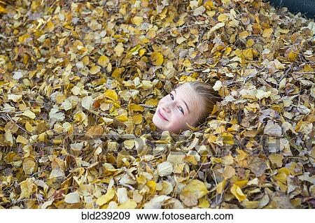 Stock Photo - Face of Caucasian girl playing in autumn leaves. Fotosearch