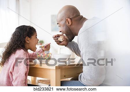 Father and daughter eating cereal at table View Large Photo Image Stock Image - Father and daughter eating cereal at table. Fotosearch