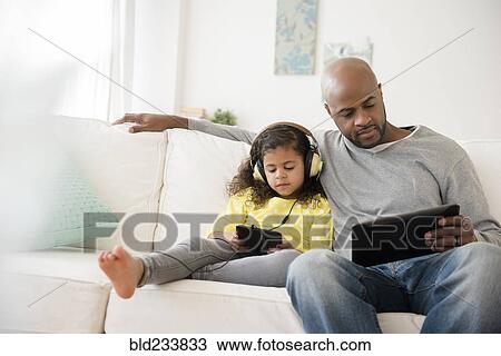 Father and daughter using digital tablets on sofa View Large Photo Image Stock Image - Father and daughter using digital tablets on sofa. Fotosearch