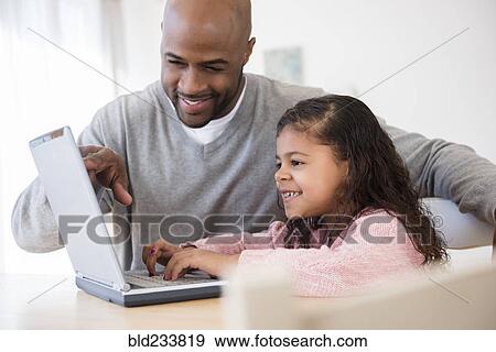 Stock Photo - Father and daughter using laptop. Fotosearch