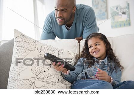 "Father and daughter watching television on sofa, " View Large Photo Image Stock Image - "Father and daughter watching television on sofa, ". Fotosearch