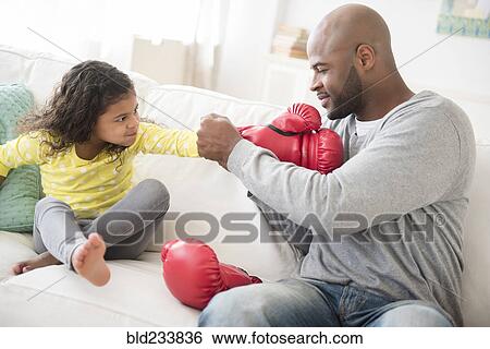 Stock Photograph - Father helping daughter with boxing gloves. Fotosearch