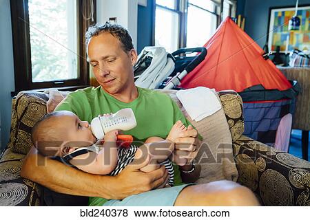 Father holding baby son drinking milk from bottle View Large Photo Image Stock Photo - Father holding baby son drinking milk from bottle. Fotosearch