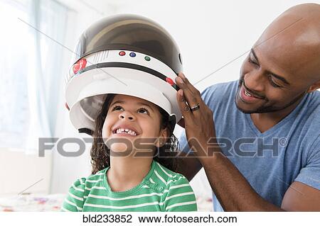 Father placing astronaut helmet on daughter View Large Photo Image Stock Image - Father placing astronaut helmet on daughter. Fotosearch
