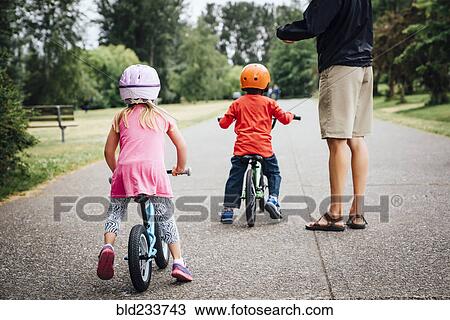 Father watching daughter and son riding bicycles View Large Photo Image Stock Image - Father watching daughter and son riding bicycles. Fotosearch