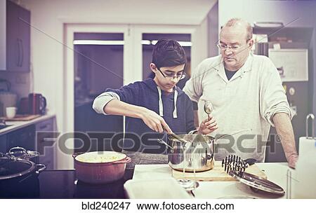 Father watching son cooking in kitchen View Large Photo Image Stock Photo - Father watching son cooking in kitchen. Fotosearch