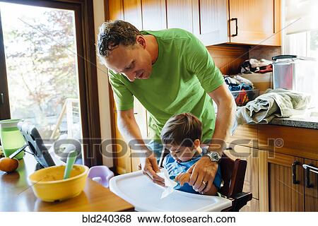 Father wiping hands of son in highchair View Large Photo Image Stock Photo - Father wiping hands of son in highchair. Fotosearch