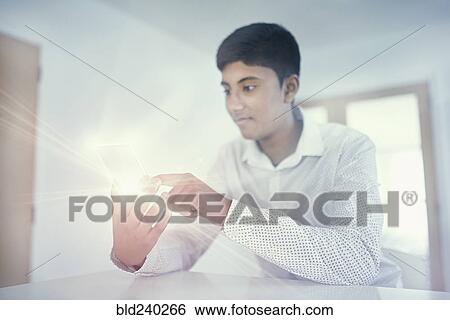 Stock Photograph - Fiji Indian boy texting on glowing cell phone. Fotosearch
