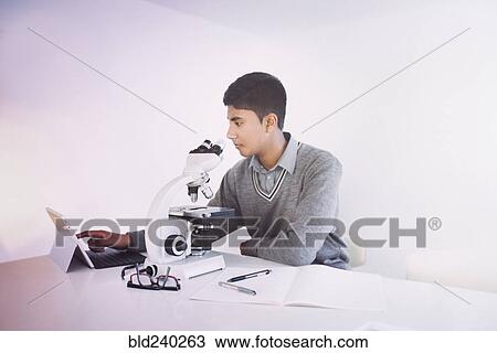 Stock Image - Fiji Indian boy using digital tablet and microscope. Fotosearch
