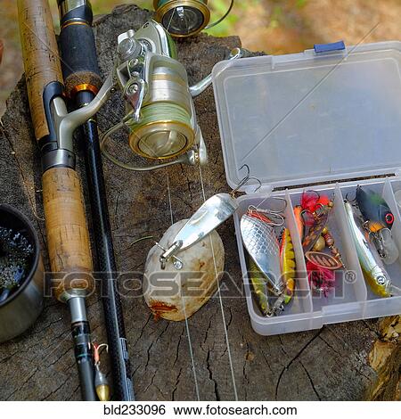 Stock Photograph - Fishing lures and fishing rod on tree stump. Fotosearch