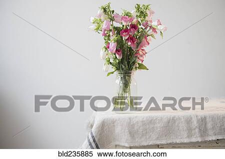 Flowers in jar of water at the edge of table View Large Photo Image Stock Photography - Flowers in jar of water at the edge of table. Fotosearch