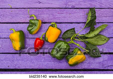 Stock Image - Fresh peppers on purple wooden table. Fotosearch