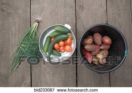 Stock Photo - Fresh vegetables and potatoes on wooden table. Fotosearch