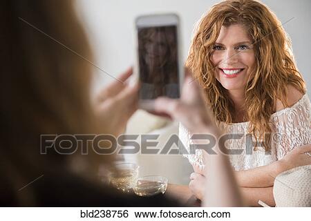 Friend photographing Caucasian woman with cell phone View Large Photo Image Stock Photograph - Friend photographing Caucasian woman with cell phone. Fotosearch