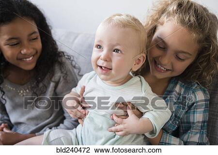 Friend watching smiling girl holding baby brother View Large Photo Image Stock Image - Friend watching smiling girl holding baby brother. Fotosearch