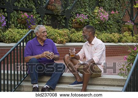 Stock Photo - Friends drinking beer in flower garden. Fotosearch