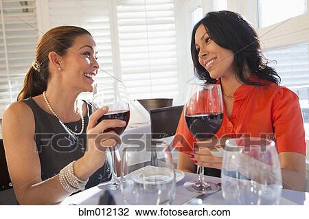 Stock Image - Friends drinking red wine in restaurant. Fotosearch
